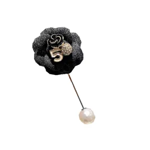 Primo piano dei dettagli della spilla in tessuto camelia nera con perla e numero elegante.
