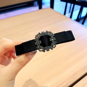Black fabric hair clip featuring a sparkling rhinestone square buckle detail close-up.