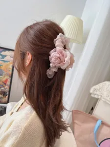 Detailed view of a pink mesh flower hair claw clip with pearl detail, worn on hair.