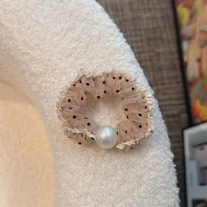 Close-up of a french vintage style mesh polka dot hair scrunchie with a large pearl detail.