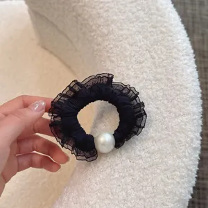 Close-up detail of black mesh ruffled hair scrunchie with large white pearl decoration.