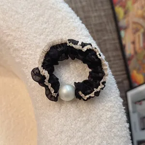 Elegant black mesh hair scrunchie with white pearl detail, perfect for chic ponytails.