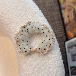 Detailed shot of a Korean style mesh polka dot hair scrunchie with delicate ruffles.
