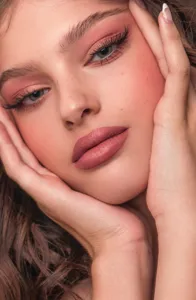 Professional makeup detail shot showing smooth facial powder, elegant blush, and matte lipstick.