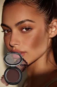 Close-up detail shot of matte bronzer powder compact with shade 05 swatch and model face.