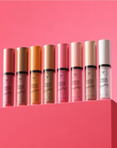 Close-up detail of shimmering lip gloss tubes in multiple sparkling shades on a pink display platform.