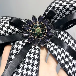 Primo piano di una spilla con fiocco pied-de-poule e centro di fiori in strass di cristallo.