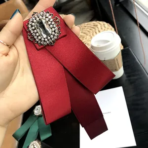 Vue détaillée d'une broche nœud en ruban satin rouge avec strass vintage et perles.
