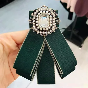Vintage green fabric bow brooch with sparkling rhinestones, pearls and a large crystal center.