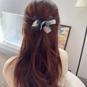 Detailed view of a chic black and white mesh bow hair clip worn gracefully in long hair.