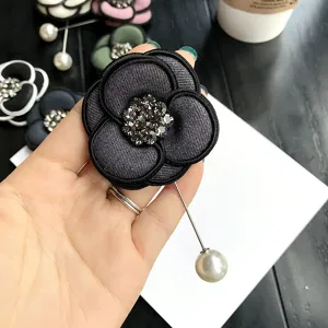 Close-up detail of vintage camellia brooch featuring sparkling rhinestones and pearl pin.
