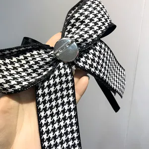 Vista di dettaglio di una spilla con fiocco pied-de-poule nero e bianco per camicie.