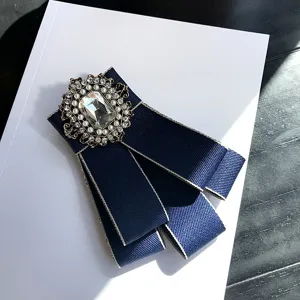 Detail shot of dark blue vintage bow brooch featuring a sparkling crystal pearl centerpiece.