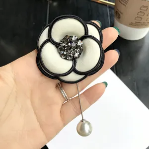 Detailed shot of elegant black and white camellia brooch with sparkling rhinestones and pearl.