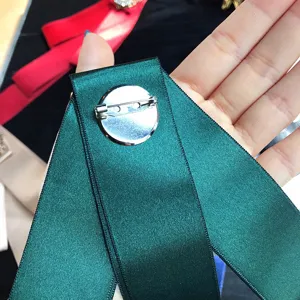 Vue détaillée de l'arrière de la broche nœud en satin vert foncé avec fermoir métallique.