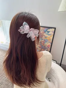 Detail shot of a Korean style mesh hair bow clip, worn on the hair in an indoor lifestyle setting.