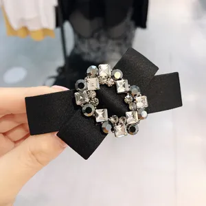 Close-up details of the black rhinestone bow hair clip, showcasing sparkling crystals.