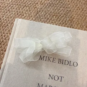 Close-up of white mesh bow hair clip, delicate organza texture for sweet hairstyles.