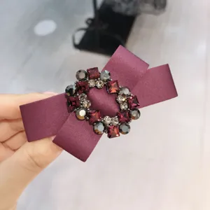 Detailed shot of a purple satin hair bow clip adorned with a sparkling crystal oval rhinestone buckle.
