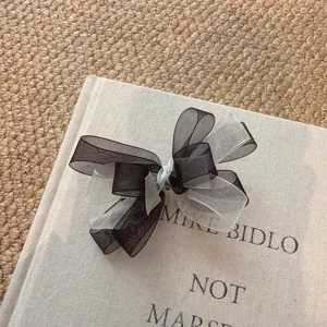 Chic black and white sheer organza bow hair clip, delicate side clip accessory detail.