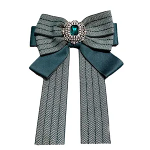 Green herringbone bow brooch with emerald gem, elegant vintage collar pin accessory for women.