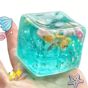 Cubo antiestrés transparente squishy con pequeñas conchas marinas para jugar y calmar.