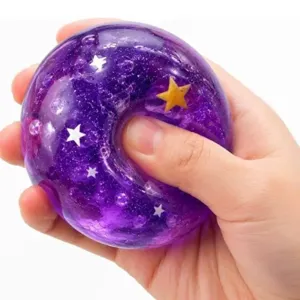 Detalle de juguete antiestrés morado con purpurina, dona transparente con estrellas.