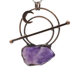 Detailed close-up of a vintage copper crystal pendant necklace with a raw purple amethyst stone.
