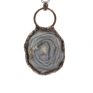 Close-up of a vintage copper wrapped raw agate crystal pendant, detailed retro jewelry texture.