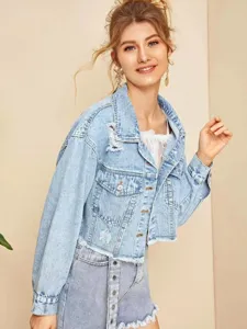Close-up van lichtblauwe denim jas met distressed gescheurde details en rafelzoom.