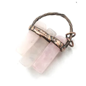 Detail view of a raw rose quartz crystal pendant with vintage copper wire wrap accessory.