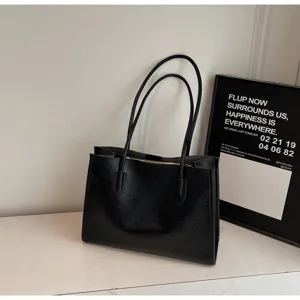 Detailed view of a minimalist black leather tote bag, perfect for daily commute and work use.