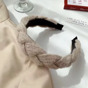 Gros plan d'un serre-tête beige tressé chic, accessoire de cheveux douillet d'hiver.