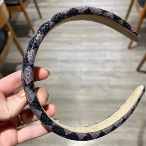 Gedetailleerd overzicht van brede lederen spons haarband met chic geruit patroon voor dagelijks.