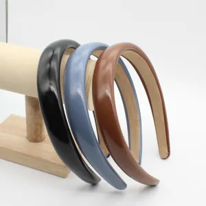 Closeup view of thick PU leather headbands in black blue and brown, smooth glossy finish detail.