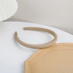 Detailed view of solid color satin padded headband in neutral beige, elegant minimalist design.