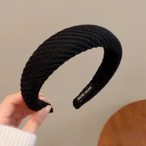 Vue détaillée du serre-tête large en tricot noir, tissu texturé, fabrication artisanale.