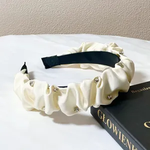 Detailed shot of white ruched rhinestone headband, elegant crystal padded hair hoop.