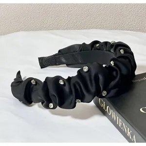 Detailed shot of black satin rhinestone pleated headband, elegant vintage hair accessory.