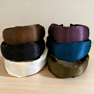 Detailed view of wide satin headbands stacked together, showing smooth texture and multiple colors.