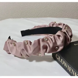 Close-up detail of a pink ruffled satin headband sparkling with crystal rhinestones.