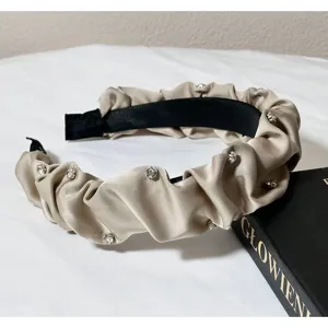 Detailed view of champagne pleated rhinestone headband with shimmering crystal gemstone decor.