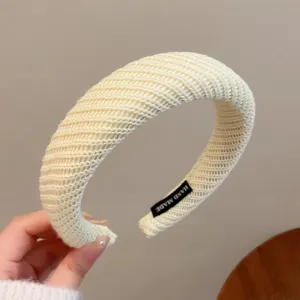 Vue détaillée d'un serre-tête large en tricot beige chic, avec une texture douce.