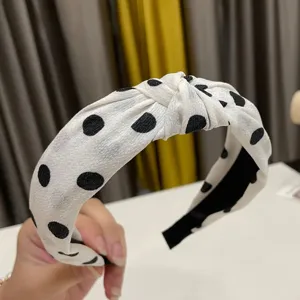 Close up of a cute white and black polka dot knotted headband, stylish hair accessory detail.