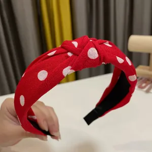 Detail shot of a red polka dot knotted headband, showing fabric texture and bow design clearly.