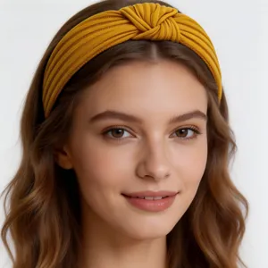 Close-up detail view of a mustard yellow knitted cotton headband featuring a chic cross knot design.