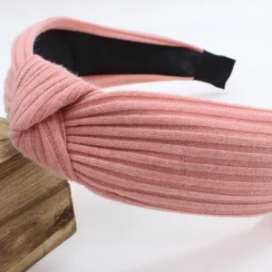 Detailed close-up view of a pink knitted wide headband featuring a stylish cross knot design.