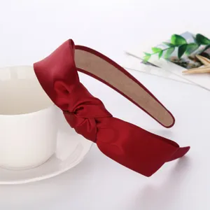 Detailed view of wine red satin knotted headband, elegant glossy hair accessory close-up.