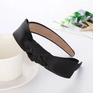 Detailed close-up of a black satin knotted headband, elegant and minimalist hair accessory.