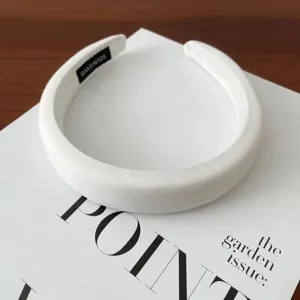 Close-up detail of white padded headband, soft fabric wrap, minimal elegant accessory.